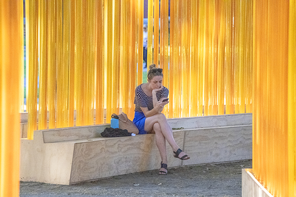 Foto Friday - a woman sitting in a bench by a yellow wall of streamers