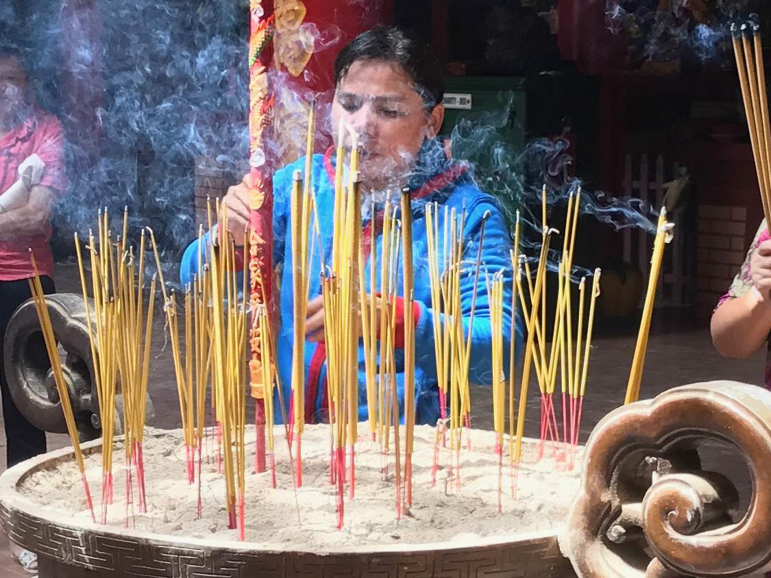 Foto Friday - a woman lighting incense sticks in a temple