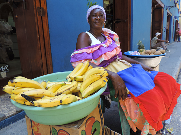 Foto Friday - a woman in a bright dress selling bananas on a street in Vartagena