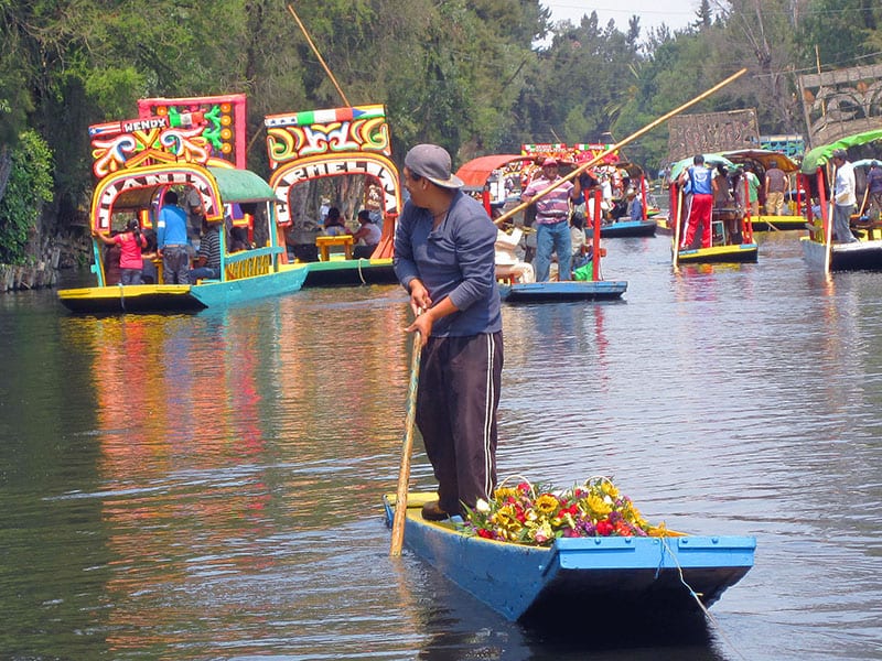 a man punting a small boat in Xochimilco Mexico