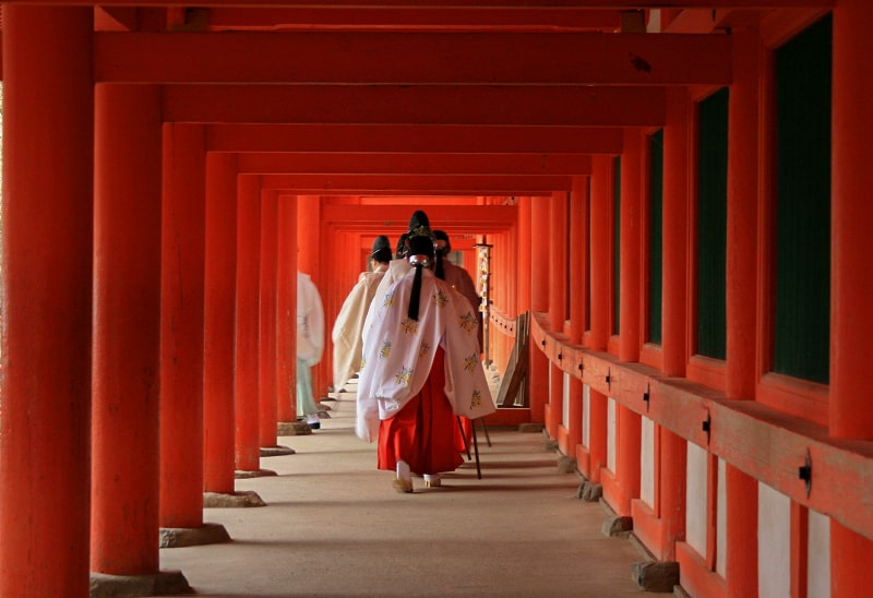 Monks walking through a red-pained hallway