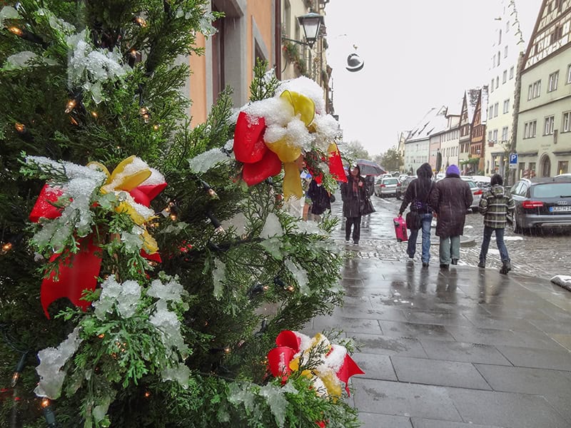 people walking past a tree covered with snow in Rothenburg Germany