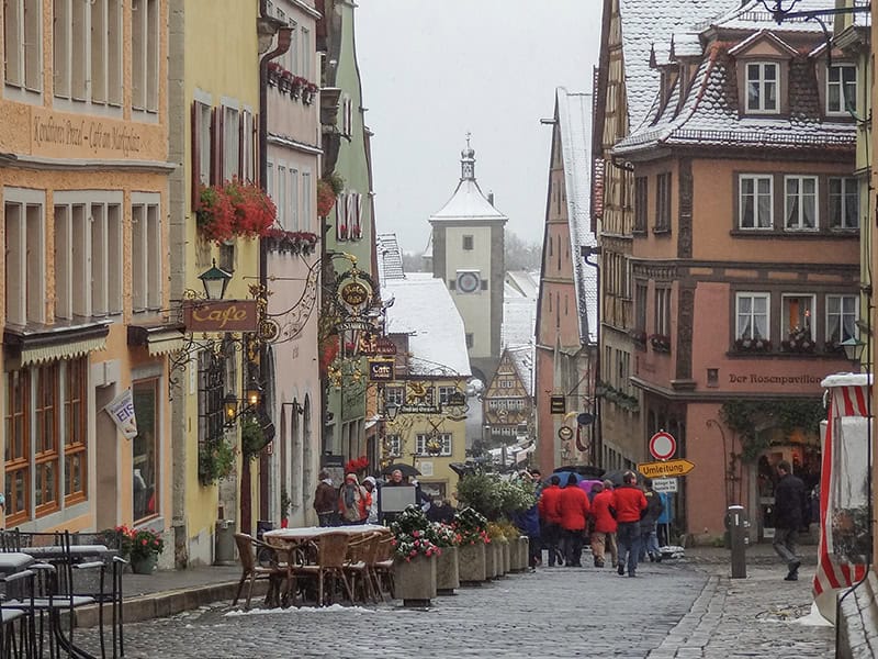 people in red jackets walking along a medieval street