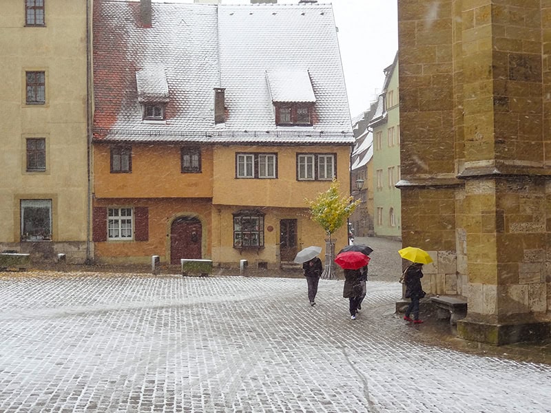 three women with umbrellas walking on a snowy street
