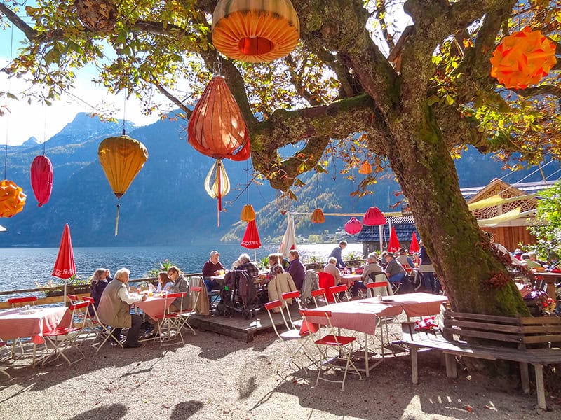 people sitting at tables near a lake in Hallstatt