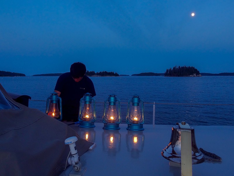 Lighting the lanterns for the night on the deck on windjammers in Maine