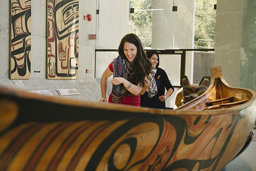 2 women alongside a canoe in a museum
