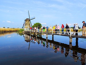 People crossing a bridge to a windmill