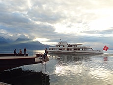 a ferry with a red flag passing a dock