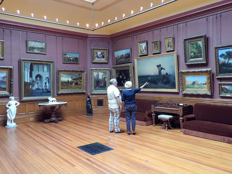 people looking at paintings in a museum with purple walls