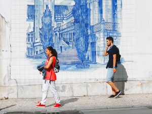 two pople walking along a tile wall in Coimbra