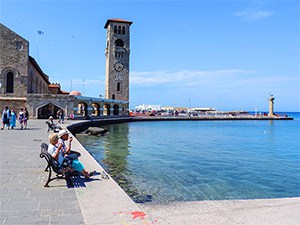 people sitting along the harbor, one of the things to do in Rhodes