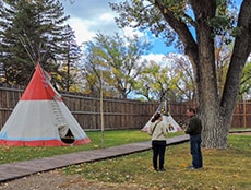 2 people by a teepee Inside Fort Benton MT