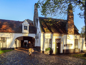 man walking along road past old white buildings