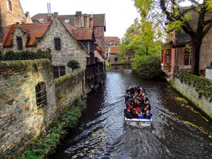 a canal boat with tourists passing old buildings