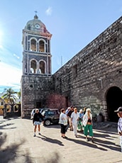 people walking by old building with a clock tower in Galapagos