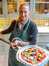 Woman holding pizza pie on an oven paddle during our Florence cooking class 