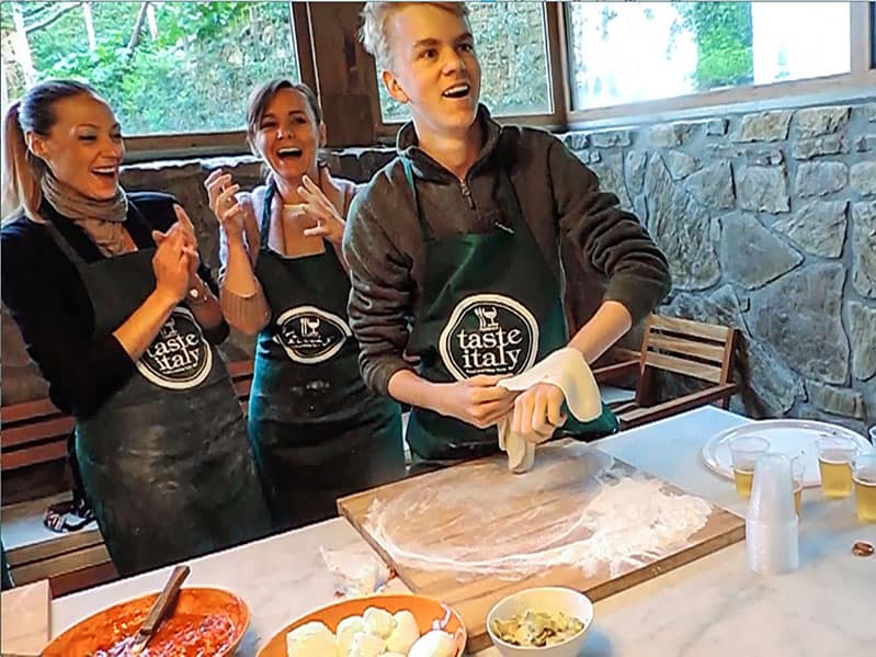 boy tossing pizza dough in a Florence cooking class 