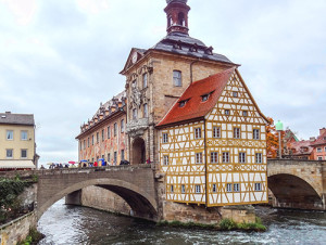 people on a bridge looking at old buildings on an island