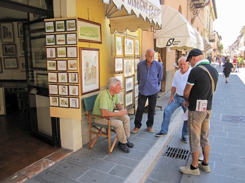 four men standing and talking outisde a prints shop in Norcia