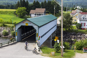 a covered bridge with people bicycling by it