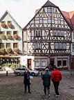 people walking by an old timber house in Germany