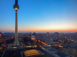 A tall television tower over a city at sunset