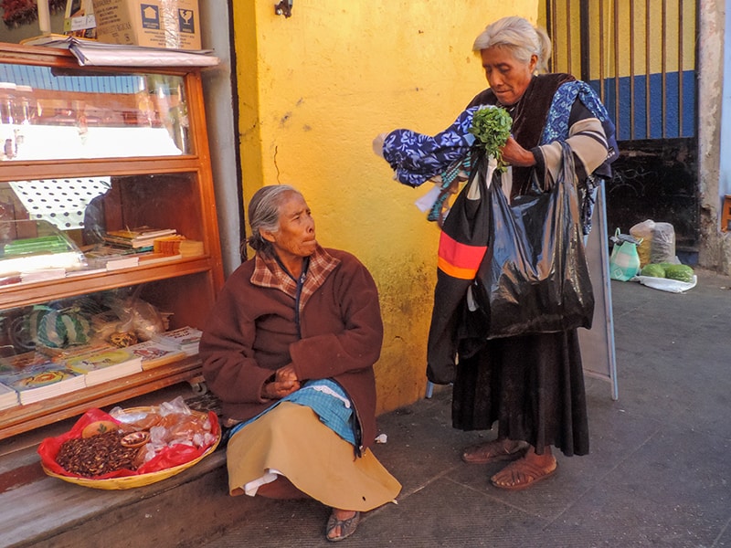 woman buying things from a street vendor, one of the things to do in Oaxaca