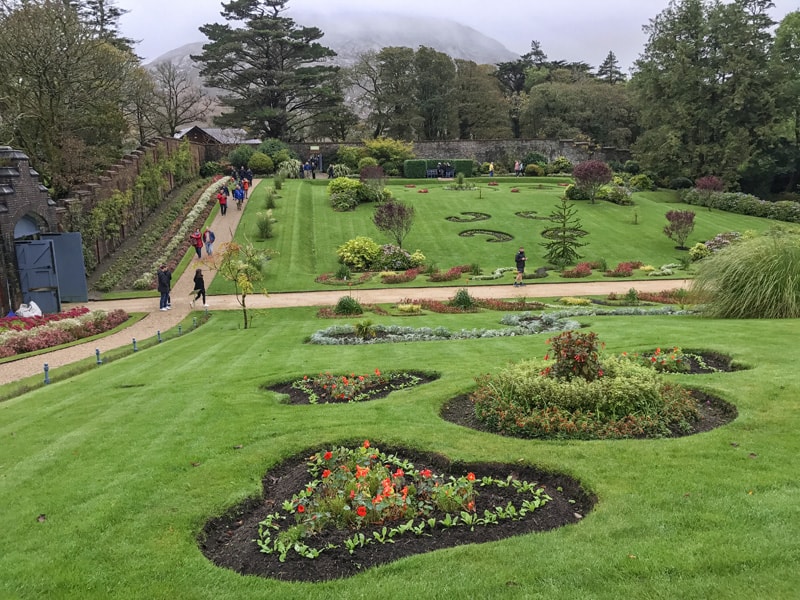 people walking through large formal gardens at Kylemore, one of the great gardens in Ireland