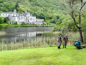 fisherman by a lake in front of an old Victorian mansion