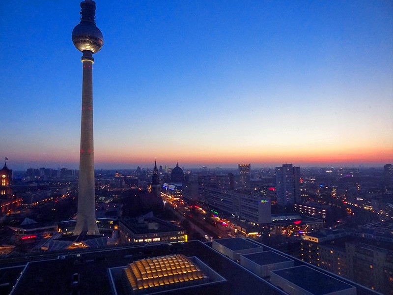 A tall television tower over a city at sunset