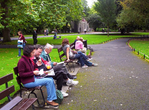 people sitting on benches in a park in Dublin