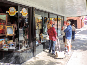 four people talking on teh sidewalk outside a shop