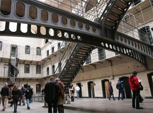 people under a walkway in an old jail building, one of the  places to visit in Dublin
