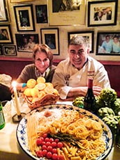2 people sitting by a display of pasta
