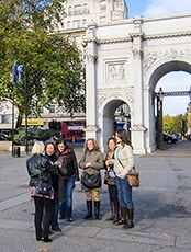 young women stading in front of a large arch