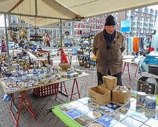 man standing by tables of plates in a second-hand market