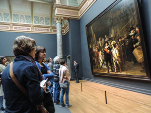 people looking at a large painting in a museum