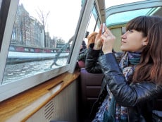 young woman taking a photo from a boat in Amsterdam