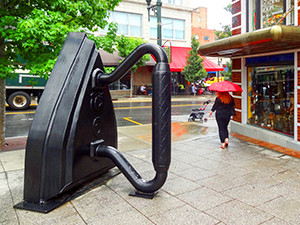 woman walking past sculpture on a sidewalk