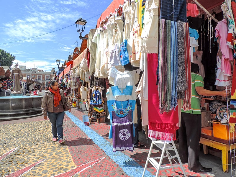 woman walking through an outdoor market, one of the fun things to do in Puebla