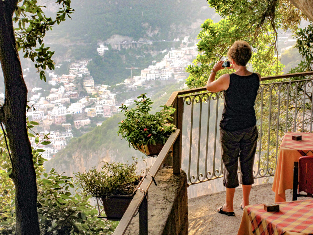 a woman taking a photo of a town in a valley