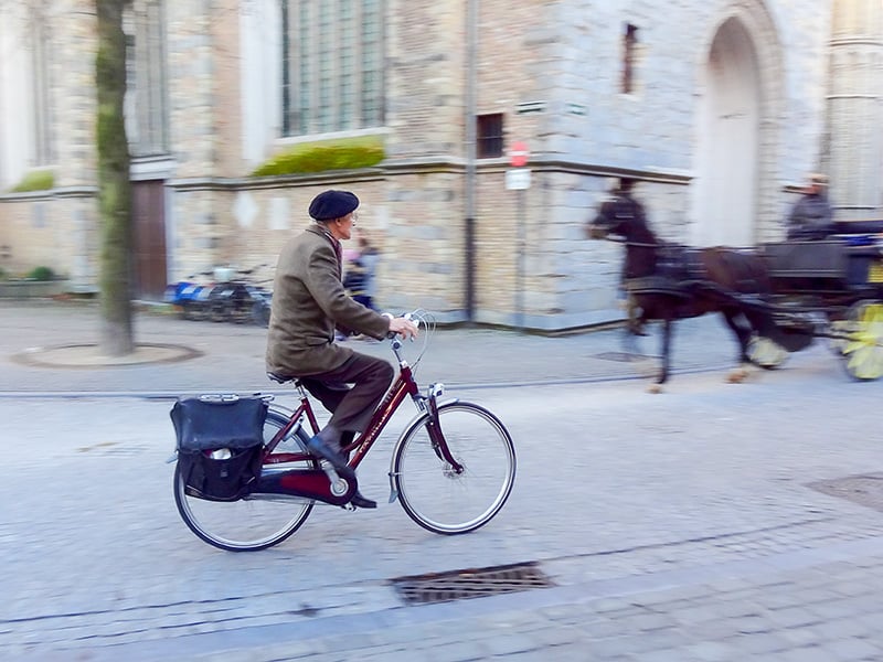 man on a bicycle Bruges, Belgium, during the best time to visit Bruges