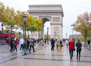 people on a sidewalk by an arch