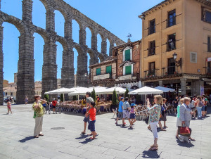 people on a plaza by an aqueduct