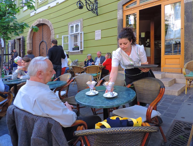 a waitress serving a man at a table, seen during 2 days in Budapest