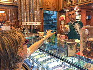 a man handing an ice cream cone to a woman -  the best gelato in Rome