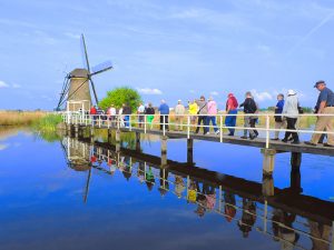 people walking on a bridge to a windmill