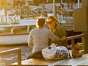 Two women sitting alongside a harbor in Sweden in Scandinavia