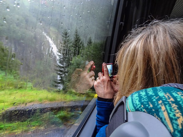 woman taking a photo out a train window in Norway in Scandinavia